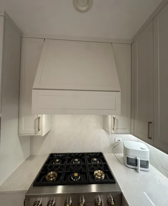 Close-up of a newly installed stove and custom-built 54-inch kitchen hood cabinet, showcasing the increased cabinet height and clean modern design after the drop ceiling removal in a Naperville kitchen remodel.