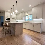 Contemporary kitchen island with bar stools, refinished light-tone oak hardwood flooring, and upgraded pendant lighting as part of Aromark’s full kitchen renovation in Naperville.