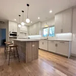 Contemporary kitchen island with bar stools, refinished light-tone oak hardwood flooring, and upgraded pendant lighting as part of Aromark’s full kitchen renovation in Naperville.