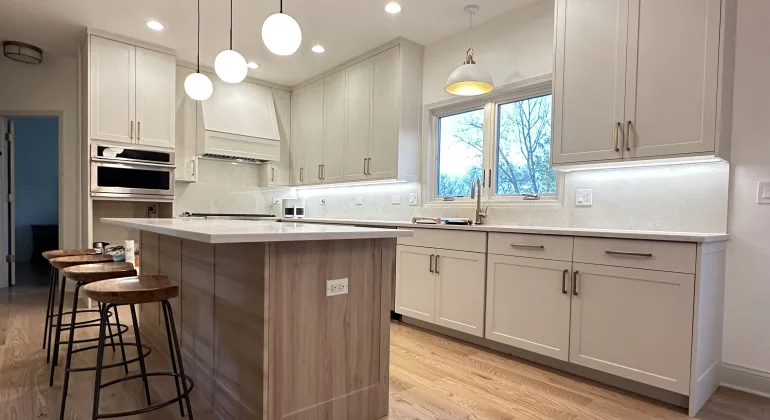 Contemporary kitchen island with bar stools, refinished light-tone oak hardwood flooring, and upgraded pendant lighting as part of Aromark’s full kitchen renovation in Naperville.