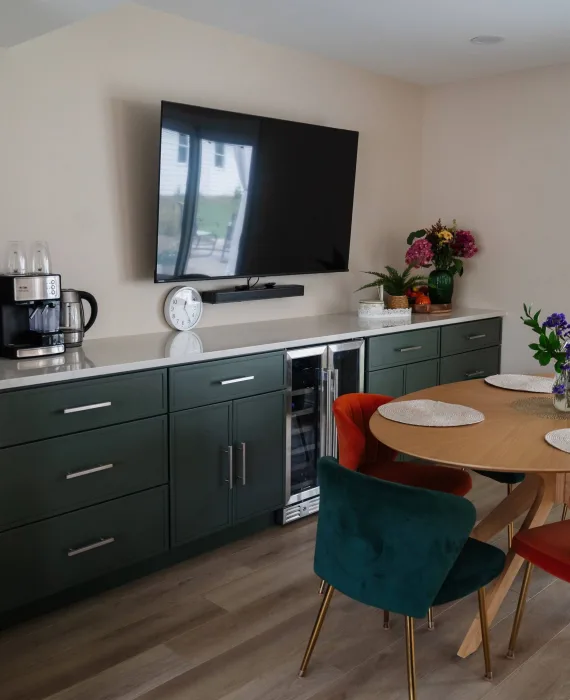 Finished open-concept kitchen with green lower cabinets, modern appliances, and a bright living area created after removing the load-bearing wall in Schaumburg.